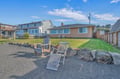Coastal vacation homes with expansive grassy yards and comfortable outdoor seating areas in a peaceful residential neighborhood.