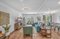 Relax in your bright, stylish living area featuring cozy teal seating and warm wood accents throughout.