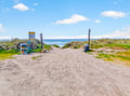 Beach access path with clear signage leads to pristine sandy coastline and ocean views.
