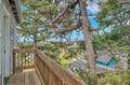 Peaceful balcony overlooks tree-lined neighborhood with distant city views and nearby swimming pool.