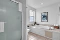 Your serene bathroom retreat features a deep soaking tub perfect for unwinding after a day of adventure, plus a glass-enclosed shower and abundant natural light.