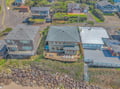 Aerial view of a charming coastal property featuring a spacious deck with outdoor dining and comfortable seating areas, surrounded by neighboring homes in a peaceful residential community.