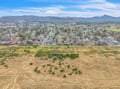 Aerial view showcasing the charming residential neighborhood nestled between rolling hills and mountain ranges, with peaceful streets winding through tree-lined communities.