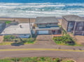 Beachfront property aerial view showing coastal homes positioned directly on sandy shore with ocean waves.