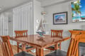 Gather around your elegant wood dining table for memorable meals with tropical art and nautical touches creating perfect vacation ambiance.