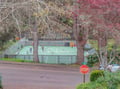 Tennis courts surrounded by autumn foliage offer recreational opportunities in this peaceful neighborhood setting.