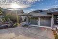 Modern property exterior showcasing the main building with attached garage and professional landscaping under a dramatic sky.