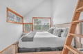 Drift off to sleep in your cozy loft bedroom, where natural light streams through windows and warm wood details create the perfect peaceful retreat.