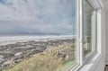 Expansive ocean views stretch endlessly beyond the coastline, with dramatic waves meeting rocky shoreline beneath cloudy skies.