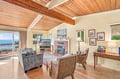Settle into your inviting living room where vaulted wood-beamed ceilings meet stunning ocean views through expansive windows. Cozy up by the fireplace or step out onto your private deck to soak in the coastal beauty.
