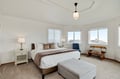 Rest peacefully in your elegant bedroom with plush bedding, thoughtful lighting, and natural light from multiple windows creating a serene retreat.