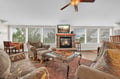 Relax in your spacious living room with plush seating, crackling fireplace, and abundant natural light streaming through panoramic windows.