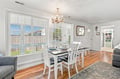 Gather around this inviting dining table beneath an elegant chandelier, where warm wood floors and natural light create the perfect setting for memorable meals together.