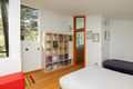 Relax in your bright, modern bedroom with stylish storage and peaceful garden views through large windows.