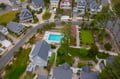 Aerial view of beachside vacation rental community featuring swimming pool and charming coastal architecture in residential neighborhood.