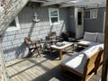 Relax on your private patio with cushioned teak seating and coastal charm beneath dappled sunlight.