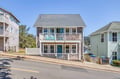 Charming coastal retreat with classic shingle siding and dual balconies featuring decorative railings, nestled on a hillside street in a coastal neighborhood with mountain views beyond.