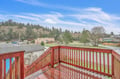 Peaceful neighborhood view from elevated wooden deck with forest backdrop and open sky.