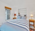 Relax in your bright, peaceful bedroom with coastal-striped linens and warm bedside lighting—your perfect retreat after a day of exploration.