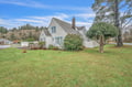 Charming coastal home with spacious lawn and mature trees, nestled in a quiet residential neighborhood.