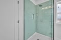 Step into your spa-like glass shower with elegant mint subway tiles, rainfall showerhead, and handheld wand for the perfect refreshing escape.