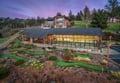 Modern mountain retreat with custom mini golf course surrounded by forest, featuring warm evening lighting and scenic hillside setting.