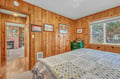 Cozy knotty pine bedroom with vintage charm, handmade quilt, and natural light streaming through your window.