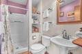 Freshen up in your charming bathroom with modern shower, thoughtful storage, and soft lavender accents for a relaxing retreat.