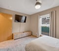 Your spacious bedroom features soft natural light, a wall-mounted TV for your entertainment, and plush carpeting underfoot. Slide open the door to access your private outdoor space whenever you need fresh air.
