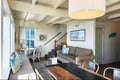 Bright, breezy coastal charm awaits in this inviting open-plan living space, where you can relax on the sofa or gather around the rustic dining table beneath vaulted ceilings.