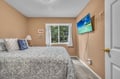 Unwind in your cozy bedroom featuring plush bedding, a wall-mounted TV for evening entertainment, and peaceful garden views.