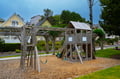 A charming community playground with wooden climbing structures and swings, perfect for family fun in this coastal neighborhood setting.