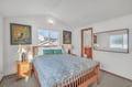 Rest peacefully in your cozy bedroom with warm wood furnishings, soft lighting, and charming artwork creating the perfect retreat.