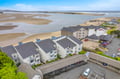 Aerial view capturing the property's direct waterfront location, with a picturesque estuary meeting expansive sandy beaches along the coastline.