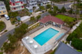 Aerial view of beachside vacation rental community featuring private swimming pool, poolside seating area, and colorful coastal homes in quiet residential setting.