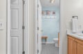 Your private bathroom features coastal charm with sea-themed artwork, warm wood accents, and thoughtful touches like a convenient wooden stool.