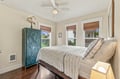 Settle into your serene bedroom with natural light streaming through bamboo shades, a ceiling fan to keep you comfortable, and unique touches like the hand-carved teal armoire that add character to your restful retreat.