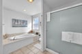 Step into your serene bathroom oasis, where a luxurious soaking tub invites you to unwind beneath soft lighting. Fresh towels await by your walk-in shower, while nautical artwork sets a calming coastal tone.