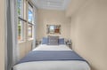 Your cozy bedroom retreat features a plush bed, soft natural light through large windows, and serene neutral tones—perfect for unwinding after a day of exploration.