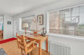 Your cozy workspace awaits with nautical charm, featuring a handcrafted desk and chair beside bright windows that bathe the room in natural light.