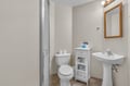 Your private bathroom features a refreshing shower, pedestal sink, and thoughtful touches like the wooden mirror and storage cabinet for all your essentials.