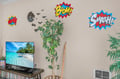 Unwind in your fun superhero-themed space with tropical vibes on screen and lush plants creating your perfect retreat.