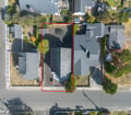 Aerial view of a residential property nestled in a quiet neighborhood, surrounded by tree-lined streets and neighboring homes. The property features a spacious yard with mature landscaping.