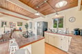 Step into your sunlit kitchen with warm wood ceilings and modern appliances, where meal prep feels effortless. Natural light streams through windows overlooking lush greenery, creating a peaceful space to start your mornings.