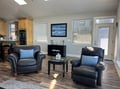Settle into plush leather chairs in this open living space, where natural light pours through multiple windows and flows seamlessly into your fully-equipped kitchen—perfect for morning coffee or evening relaxation.
