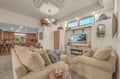 Sink into plush seating in your open-concept living space, where vaulted ceilings and coastal décor create a serene island retreat. The fireplace and entertainment center invite relaxed evenings after beach days.