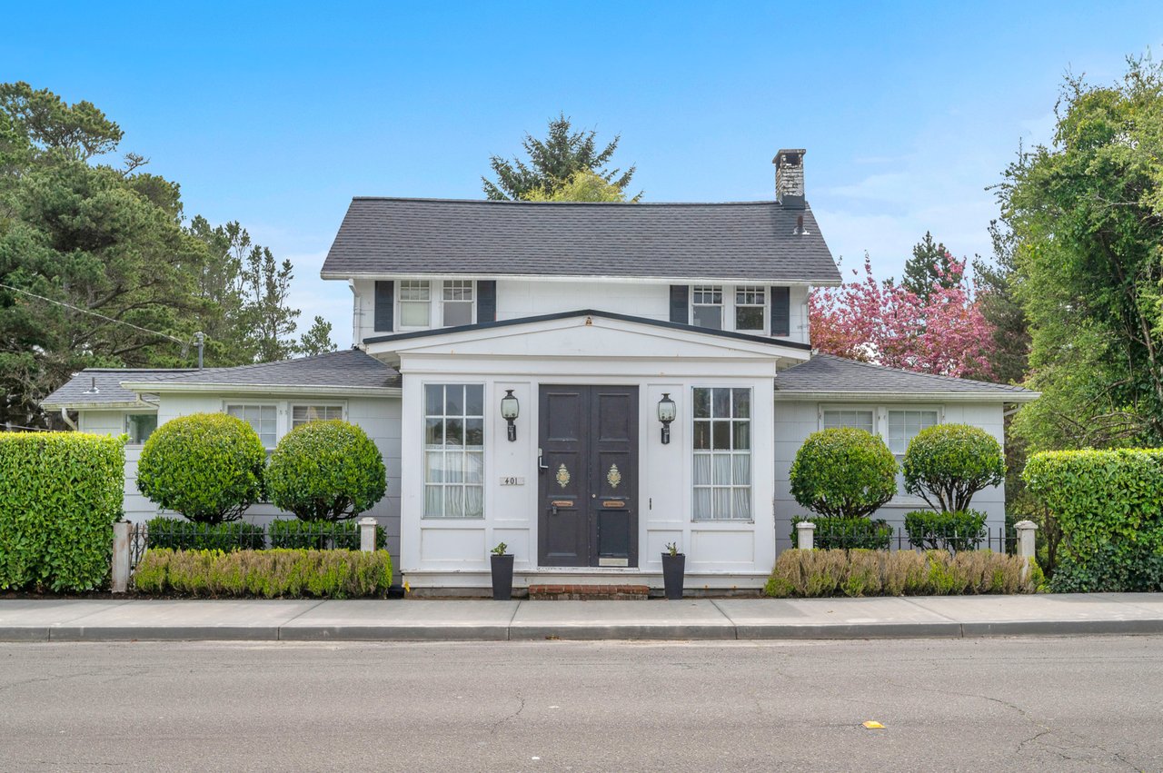 Charming white colonial home with manicured landscaping and welcoming front entrance in a peaceful residential setting.