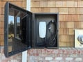 Electric vehicle charging station mounted on exterior brick wall with weatherproof housing for convenient eco-friendly travel.