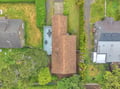 Aerial view showing the property nestled in a quiet residential neighborhood, surrounded by lush greenery and neighboring homes, with easy street access for arrival.