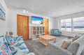 Unwind in your bright beachfront living room with ocean views through large windows and comfortable seating.